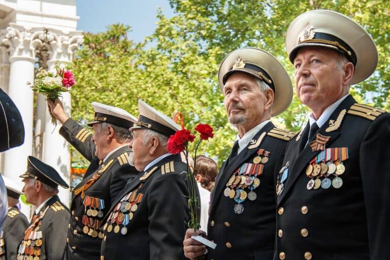 Veterans in uniform proudly displaying medals and holding flowers during a Memorial Day ceremony, honoring military service and fallen heroes.