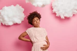 pregnant woman feeling pregnancy brain fog depicted by clouds over her head